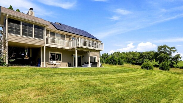 A two-story house with a covered porch and a large lawn.
