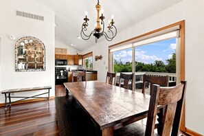 A spacious kitchen with wooden cabinets, a large dining table, and a view to the outdoors.
