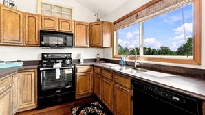 A kitchen with wooden cabinets, a black stove, a microwave, and a dishwasher.