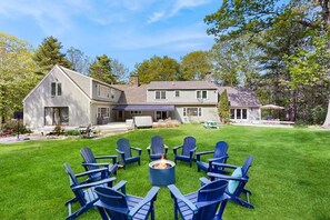A two-story house with a fire pit and chairs in the front yard. - Lands End House at Cape Porpoise with Hot Tub (Kennebunkport)