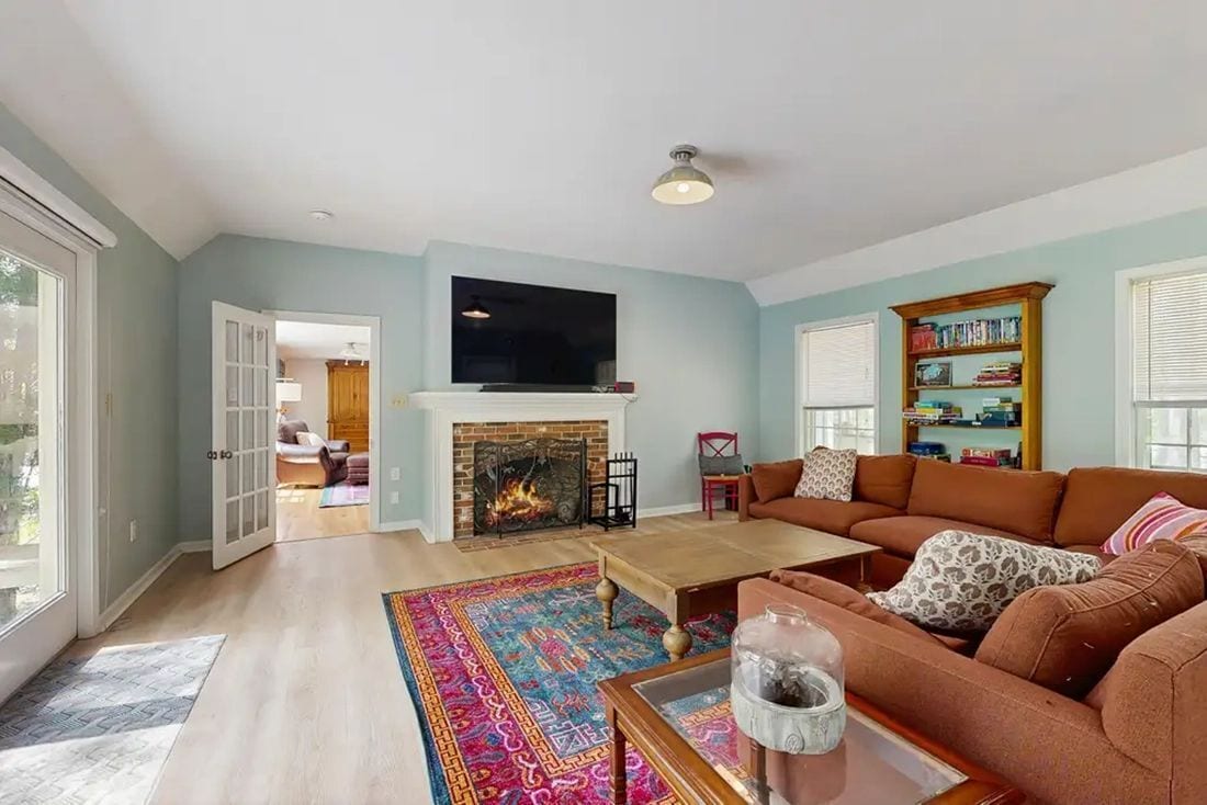 A living room with a fireplace, a sofa set, a coffee table, and a bookshelf.