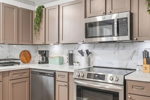 Une cuisine moderne dotée d’appareils électroménagers en acier inoxydable, de plans de travail en marbre et d’armoires en bois.