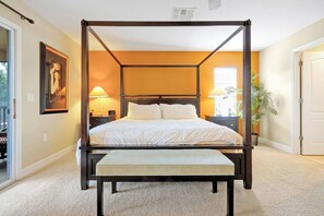 A four-poster bed with a bench in the center, a nightstand with a lamp, and a framed picture on the wall. - Peaceful Private View Disney Villa Pool Spa (Davenport)