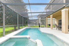 Una piscina amb terrassa coberta, mobles d'exterior i vista a un edifici residencial.