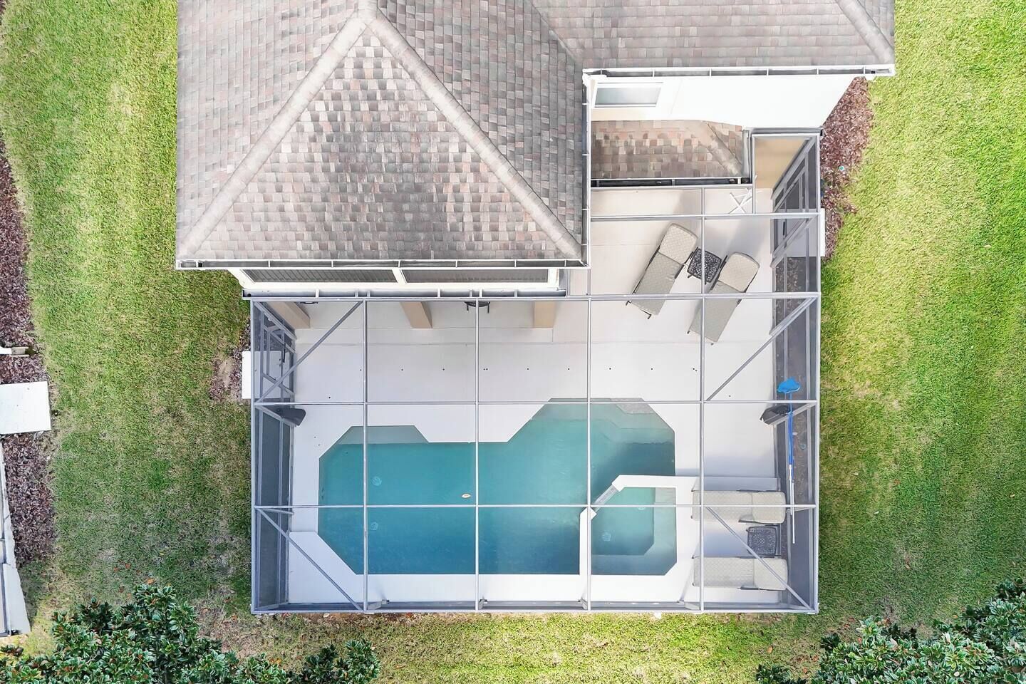 A residential property with a swimming pool, a covered patio area, and a fenced yard.
