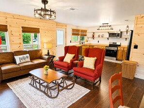 Ein gemütliches Wohnzimmer mit einer Couch, Sesseln, einem Couchtisch und einem Kamin.