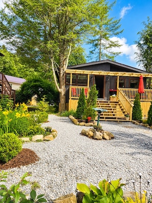 A cabin with a wooden deck, a covered porch, and a gravel pathway. - New Cottage, Premium Comfort, Blue Ridge Mtns, Ski, Golf (Newland)