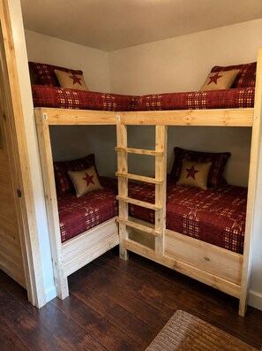 Ein Stockbett mit einer Holzleiter, zwei Kissen mit Sternenmuster und einer gemusterten Bettdecke.