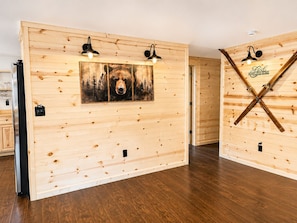 Une pièce aux murs recouverts de lambris en bois, avec un plancher en bois et un tableau représentant un chien.