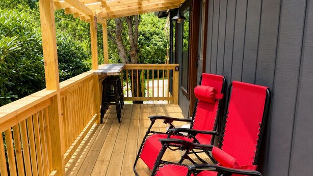 A wooden deck with a pergola, two red chairs, and a table. - New Cottage, Premium Comfort, Blue Ridge Mtns, Ski, Golf (Newland)