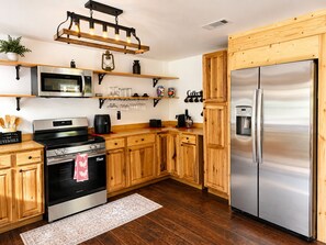 Eine moderne Küche mit Holzschränken, Edelstahlgeräten und einer eingebauten Mikrowelle.
