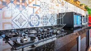 Una cocina con estufa a gas, microondas y una variedad de azulejos estampados en la salpicadera.