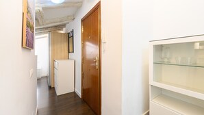 A narrow hallway with a wooden door, a small refrigerator, and a glass shelf with glasses. - (FER3452) 1 bedroom penthouse in Moncloa (Madrid)