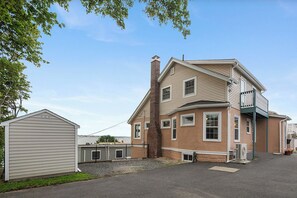 A two-story house with a large chimney, a garage, and a small shed. - The Nahant Perch: ocean view, walk to beach (Nahant)