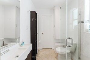 A modern bathroom with a glass shower enclosure, a white toilet, and a sink with a mirror. - SoFi Ocean Drive Villa | Direct Beach Access (Miami)