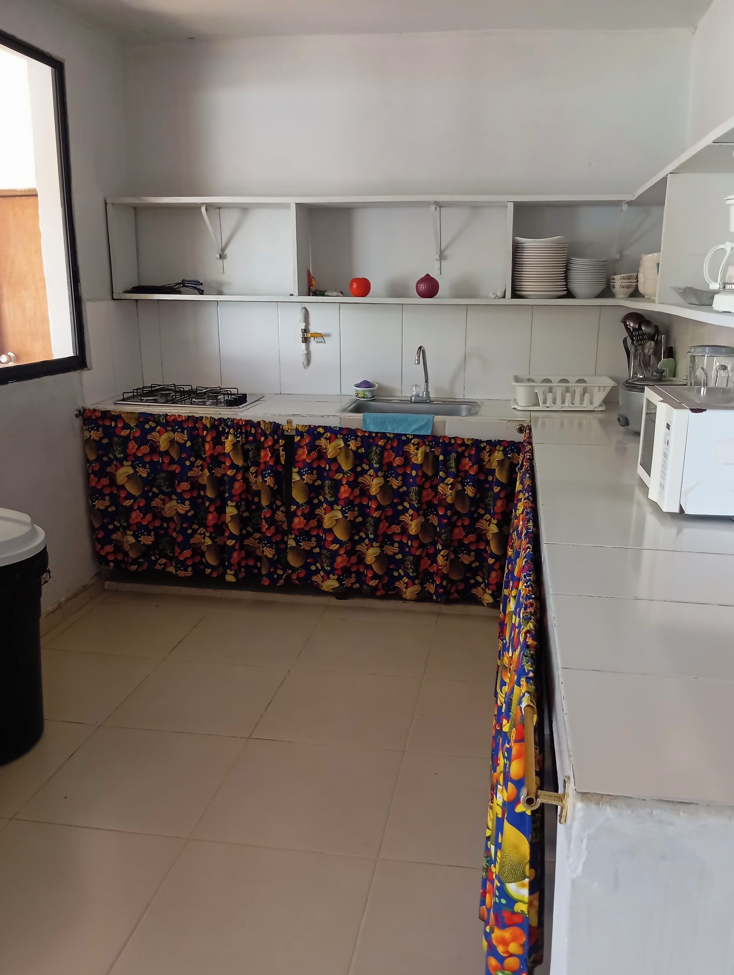 A kitchen with a gas stove, sink, and white cabinets.