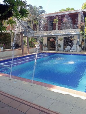 A swimming pool with water features and a building with balconies. - Welcome to tropical paradise with private pool and barbecue space (Sopetrán)