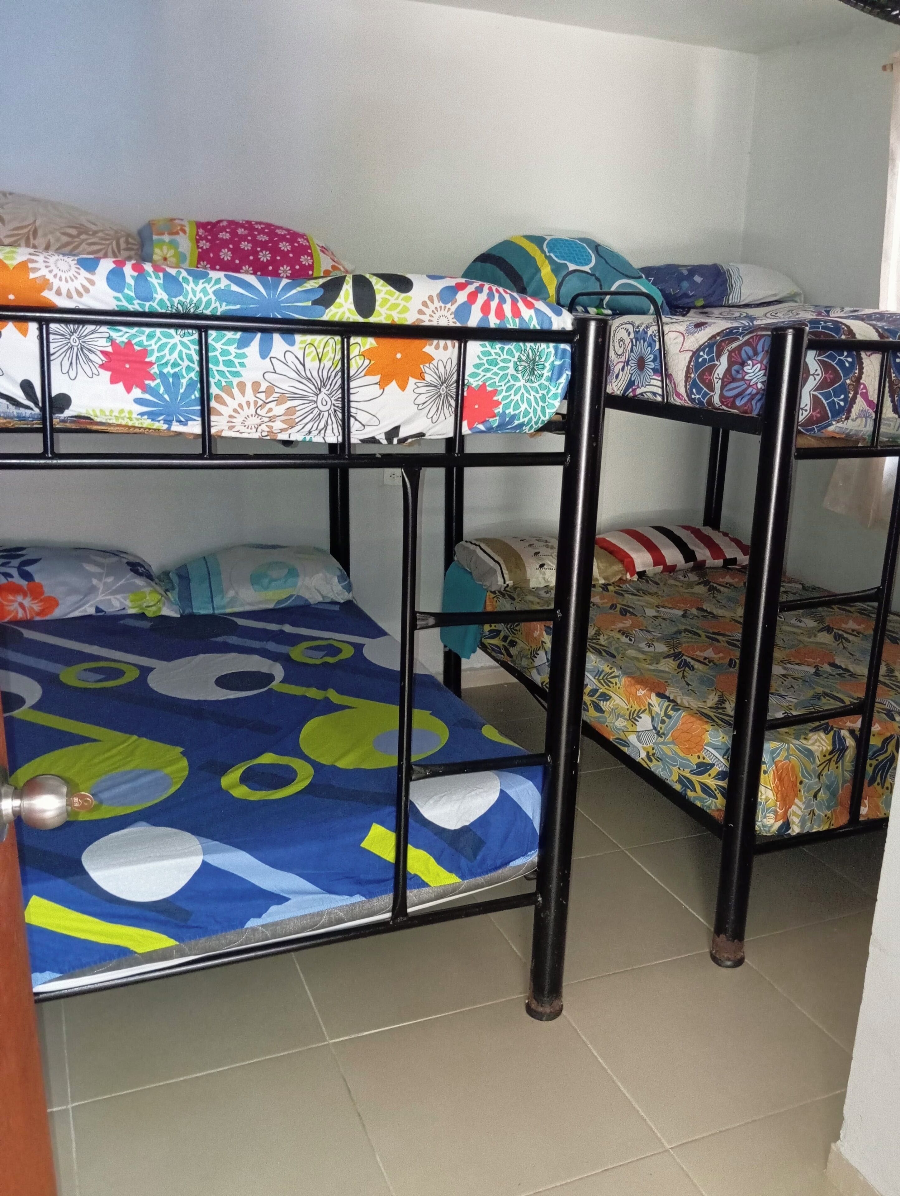Una cama litera con ropa de cama de colores y estructura metálica.