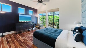Ein modernes Schlafzimmer mit Bett, Fernseher, Schreibtisch und Blick ins Freie.