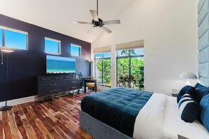 A modern bedroom with a bed, a TV, a desk, and a view of the outdoors. - Waterfront Luxe Smart Home | Pool | Gym | Spa (Lantana)