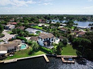 A residential area with houses, a swimming pool, and a dock extending into a body of water. - Waterfront Luxe Smart Home | Pool | Gym | Spa (Lantana)