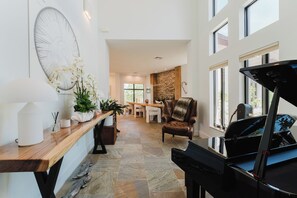 Een ruime woonkamer met een piano, een eettafel en een gezellige zithoek.