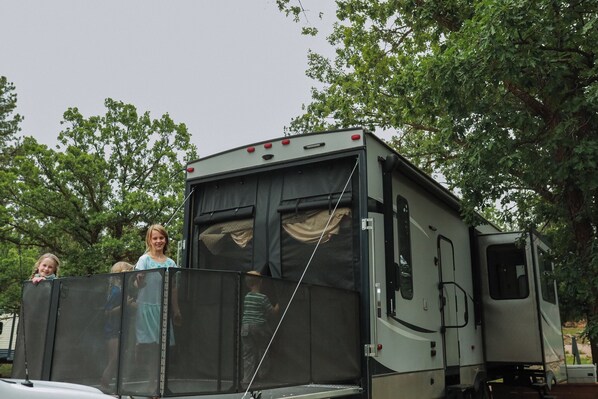 A recreational vehicle with a screened porch area.