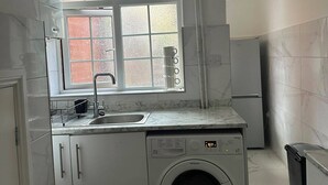 Cocina compacta con lavadora integrada, ventana con vidrio esmerilado y un lavamanos.