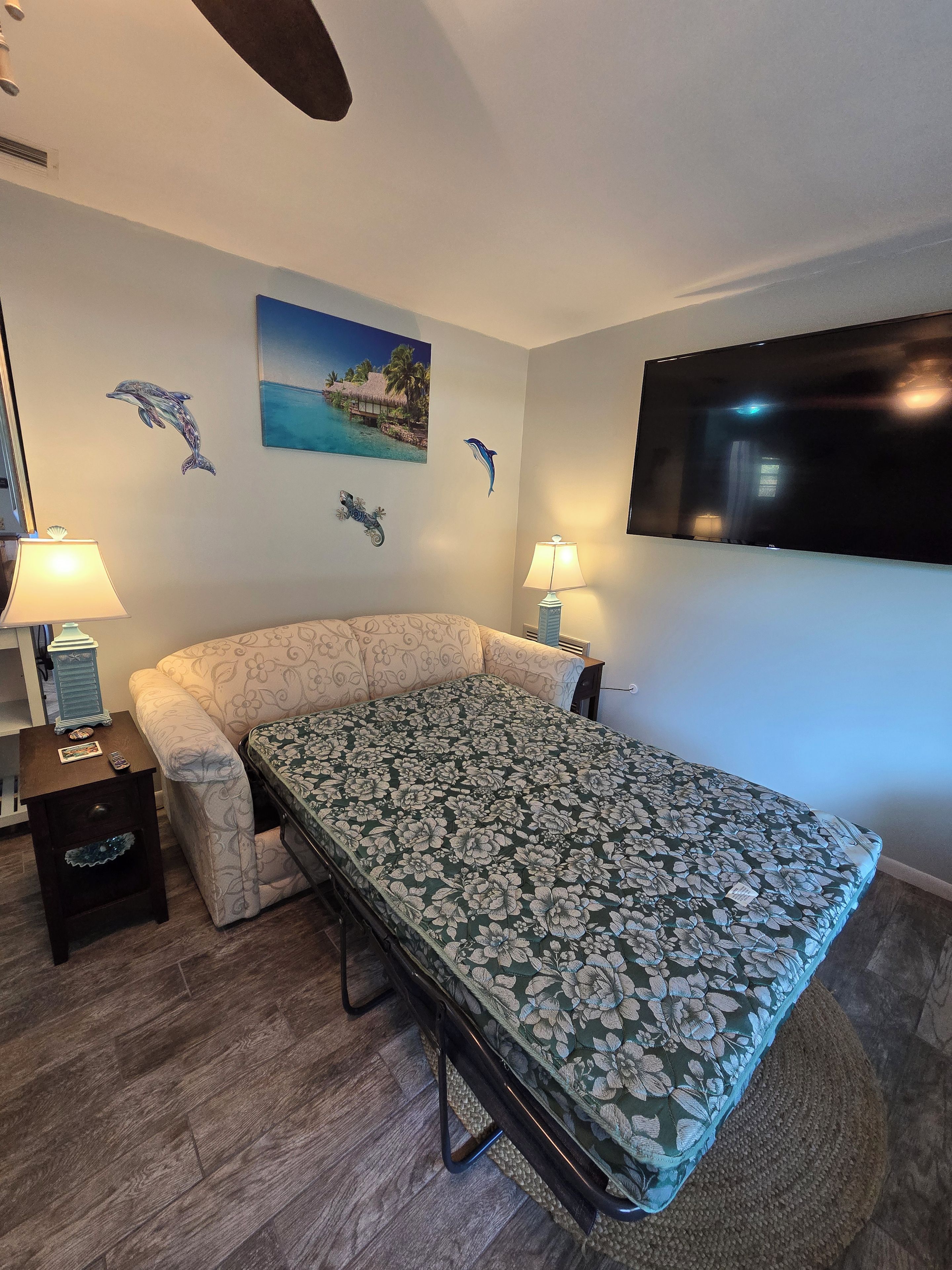 Une chambre à coucher comprenant un lit, deux tables de chevet, un téléviseur et des œuvres d’art murales.