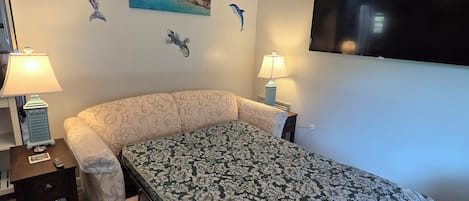 Une chambre à coucher comprenant un lit, deux tables de chevet, un téléviseur et des œuvres d’art murales.