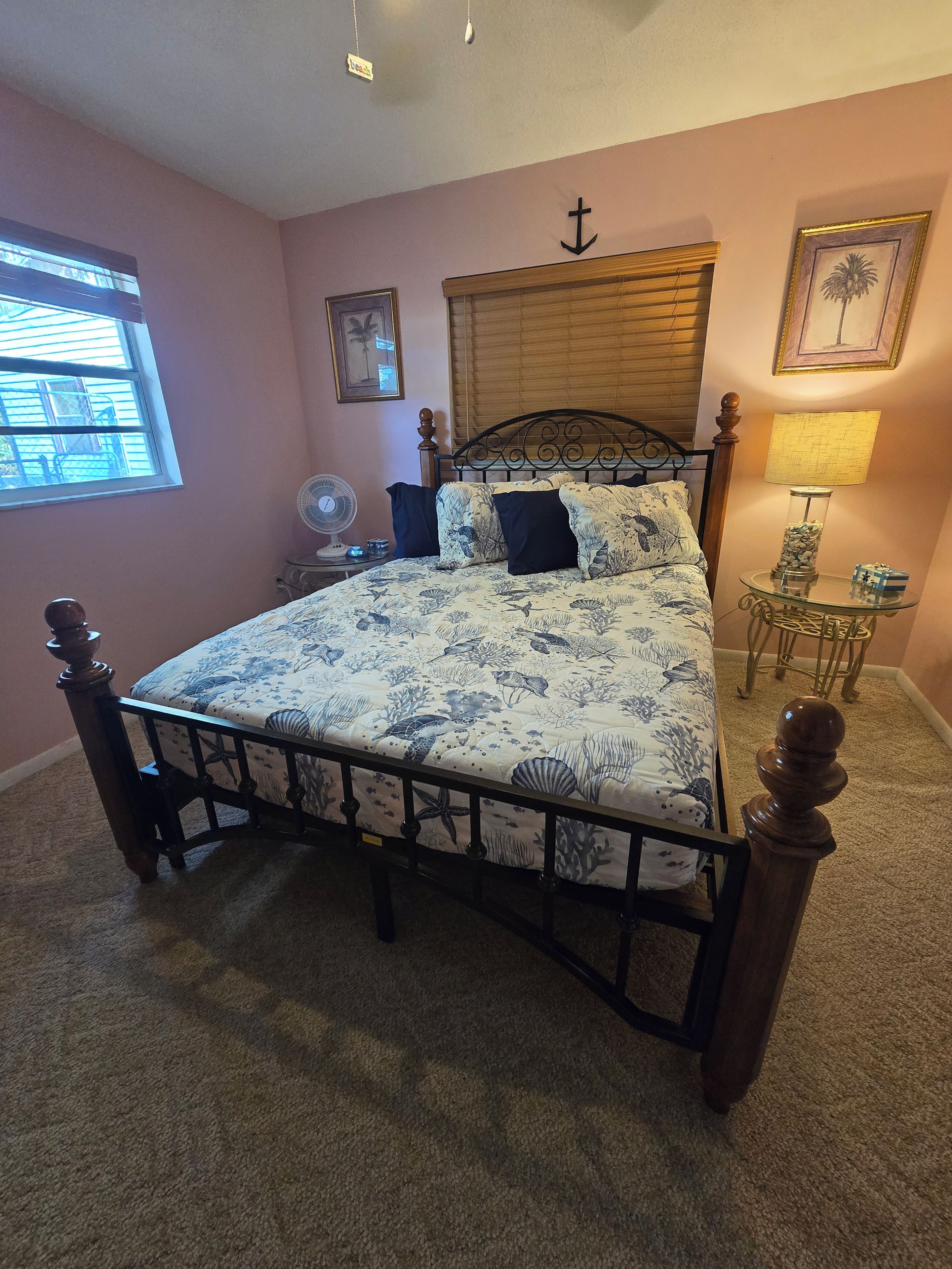 Une chambre à coucher avec un lit, une table de chevet, une lampe et une fenêtre.