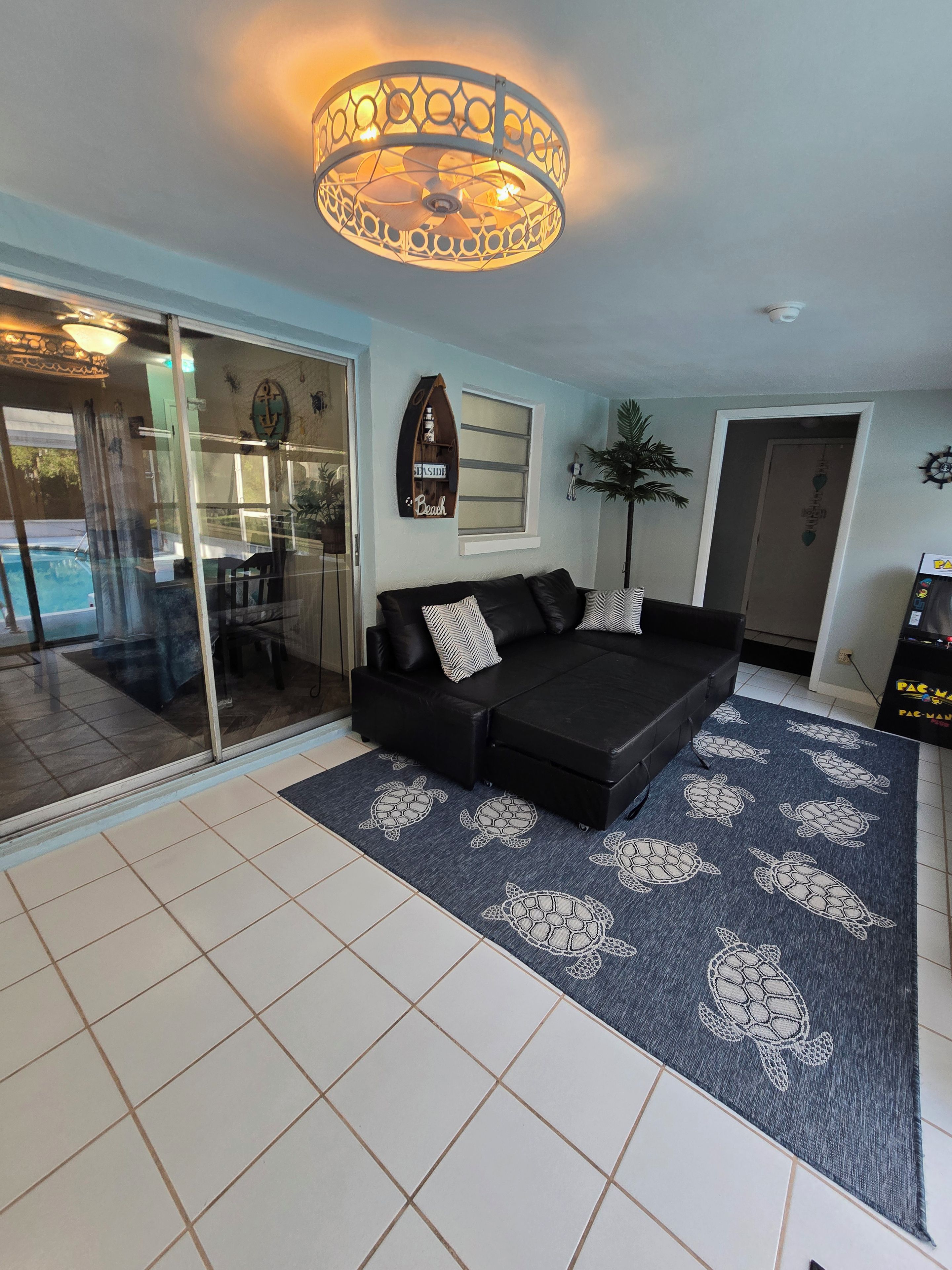 A modern living room with a black sofa, a patterned rug, and a ceiling light fixture.