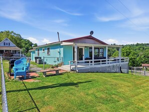 Ein kleines Haus mit Veranda, umzäuntem Garten und Grill.