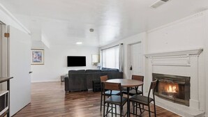 Una sala de estar con chimenea, un sofá, un televisor y un comedor con sillas.