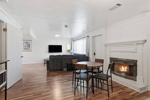 Ein Wohnzimmer mit Kamin, einer Couch, einem Fernseher und einem Essbereich mit Stühlen.