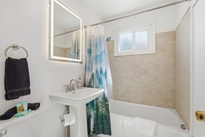 Ein Badezimmer mit Waschbecken, Spiegel und Badewanne.
