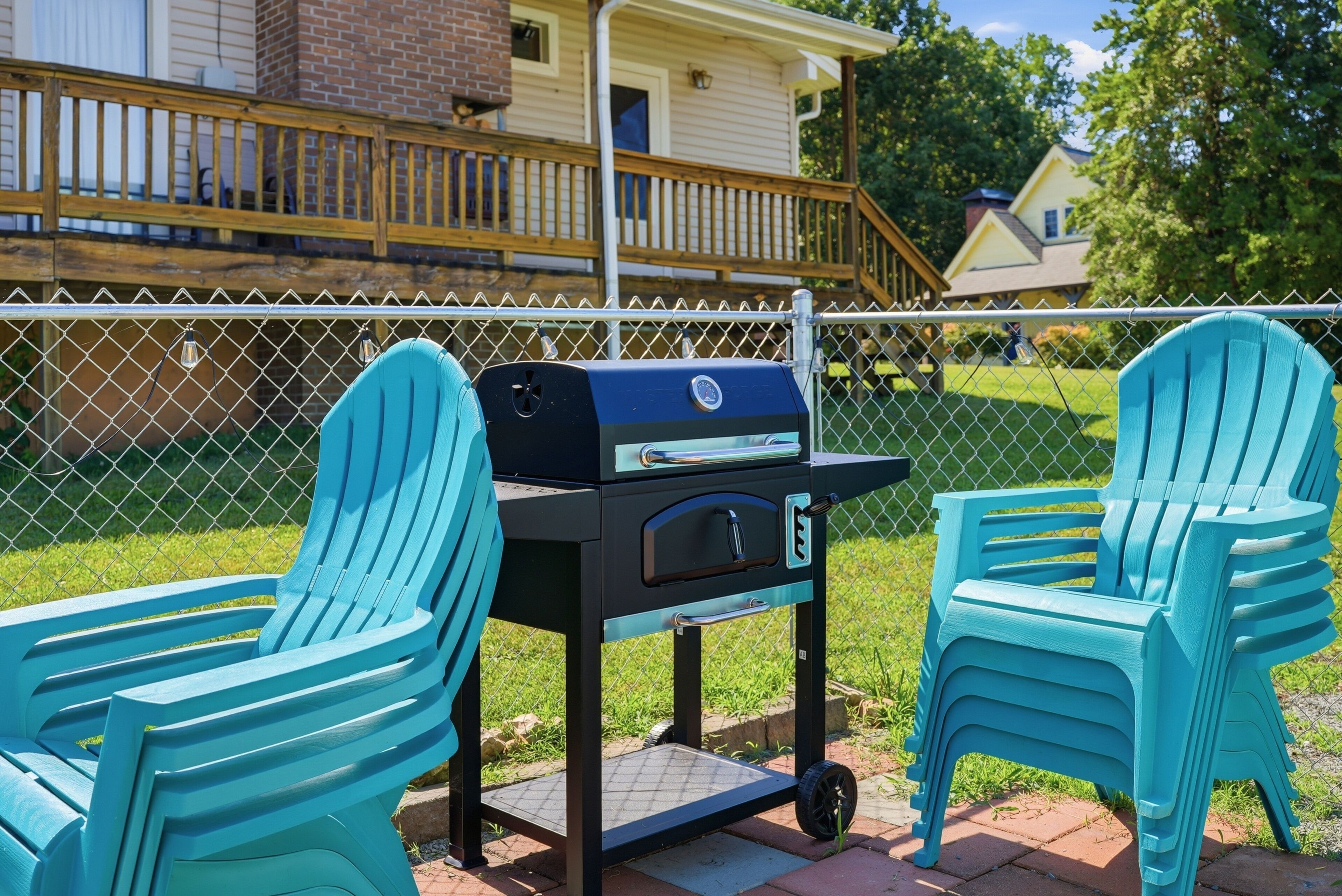 Een terras met een barbecue, twee stoelen en een omheining.