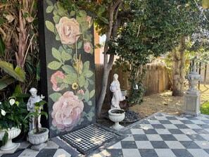 Ein Garten mit Schachbrettmuster-Boden, dekorativem Zaun und einer Statue.
