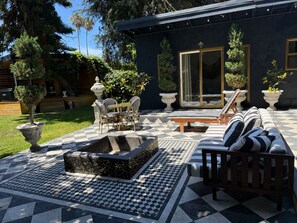 Eine Terrasse mit Schachbrettmuster-Boden, Gartenmöbeln und Blumentöpfen.