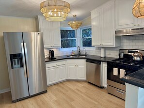 A modern kitchen with stainless steel appliances, white cabinetry, and a large window. - Private retreat w hot tub, sauna & cold plunge steps from La Jolla Shores Beach (San Diego)