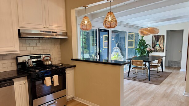 A modern kitchen with a stove, oven, and white cabinets. There are two pendant lights above the island. - Private retreat w hot tub, sauna & cold plunge steps from La Jolla Shores Beach (San Diego)