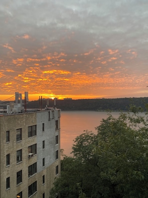 Un edificio con varias ventanas y techo plano, con vista a un cuerpo de agua y un cielo al atardecer.