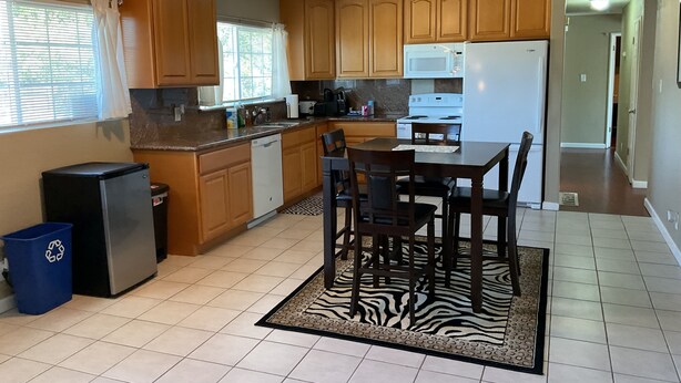 A kitchen with wooden cabinets, a refrigerator, a microwave, and a dining table with chairs. - 3-bedroom house in lovely Stockton with cool AC and comfort (Stockton)