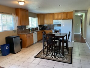 A kitchen with wooden cabinets, a refrigerator, a microwave, and a dining table with chairs. - 3-bedroom house in lovely Stockton with cool AC and comfort (Stockton)