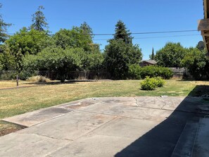 A backyard with a concrete patio, a lawn, and trees. - 3-bedroom house in lovely Stockton with cool AC and comfort (Stockton)