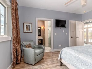 Een slaapkamer met een bed, een stoel, een televisie en een deur naar een badkamer.