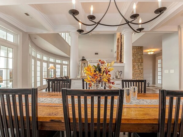 Un coin repas avec une table et des chaises en bois, un lustre et un vase de fleurs.