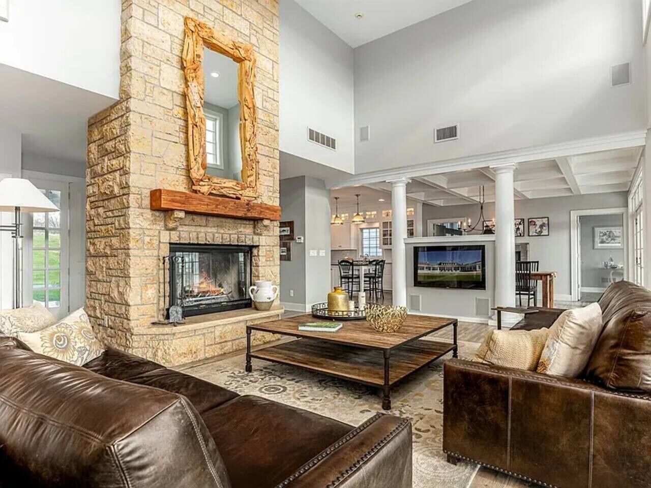 A spacious living room with a stone fireplace, leather sofas, and a large television.