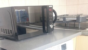 A kitchen with a microwave, a washing machine, and a kettle. - Cozy London Apartment With City Views (London)