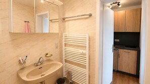 Un baño moderno con lavamanos, espejo, toallero y un inodoro a la vista.